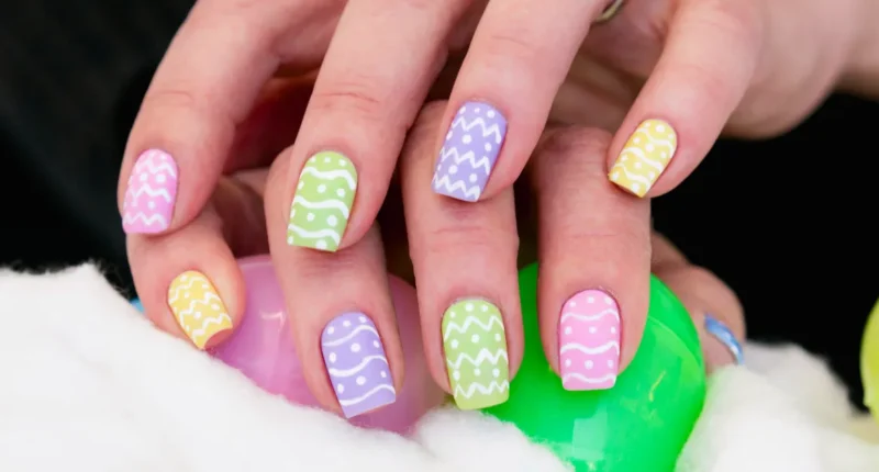 A playful and colorful Easter-inspired nail art design featuring a variety of pastel colors like pink, green, purple, and yellow, each nail with a unique Easter egg pattern of wavy lines and dots, evoking the joy and creativity of an Easter egg decorating session.