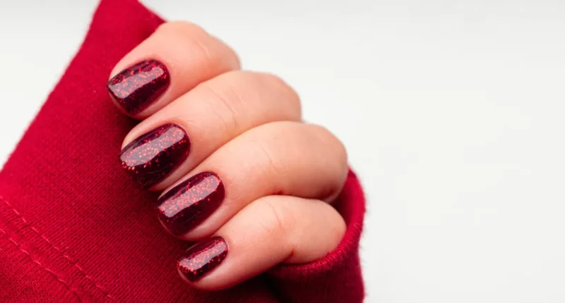 Deep red short nails dusted with glitter, creating a romantic and textured effect that's perfect for a cozy and intimate Valentine's Day celebration