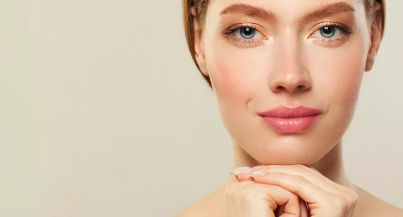 A woman's portrait highlighting her natural makeup look with subtle pink tones and a hint of golden shimmer around her eyes, embodying a graceful and minimalist beauty aesthetic.