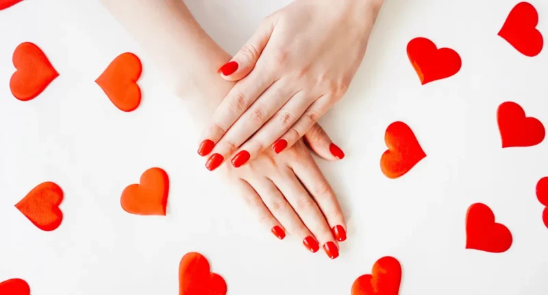 Short nails with a glossy red base featuring delicate heart tips perfect for Valentine's Day romance, showcasing a playful and affectionate design.