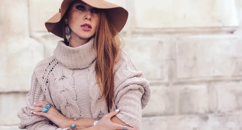 Stylish woman in a chunky knit turtleneck sweater and wide-brimmed hat, accessorized with statement turquoise jewelry, showcasing a sophisticated boho look for winter.