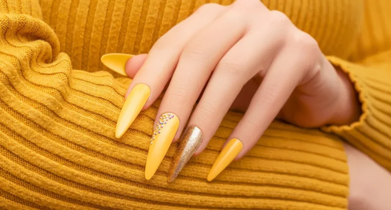 Vibrant sunshine yellow stiletto nails with a glittery accent, a daring and lively choice to stand out during the dreary days of January