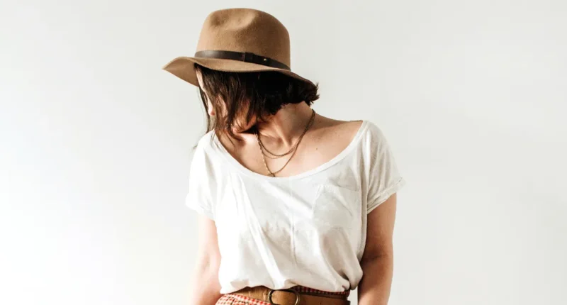 A casual yet chic look featuring a simple white tee paired with a tailored brown fedora, perfect for a laid-back yet stylish spring day out