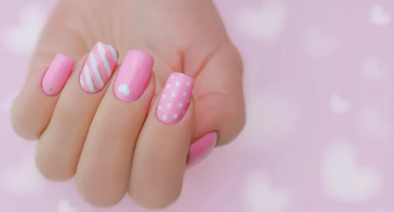 Promotional banner for '14 Pink Valentine's Day Nail Design Inspirations,' featuring a bold pink background with whimsical white lettering and star accents