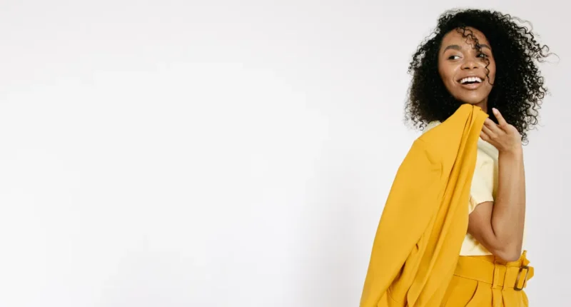 A cheerful woman wearing a bright yellow blazer over a casual yellow top, her smile reflecting the joy and color of the spring season.